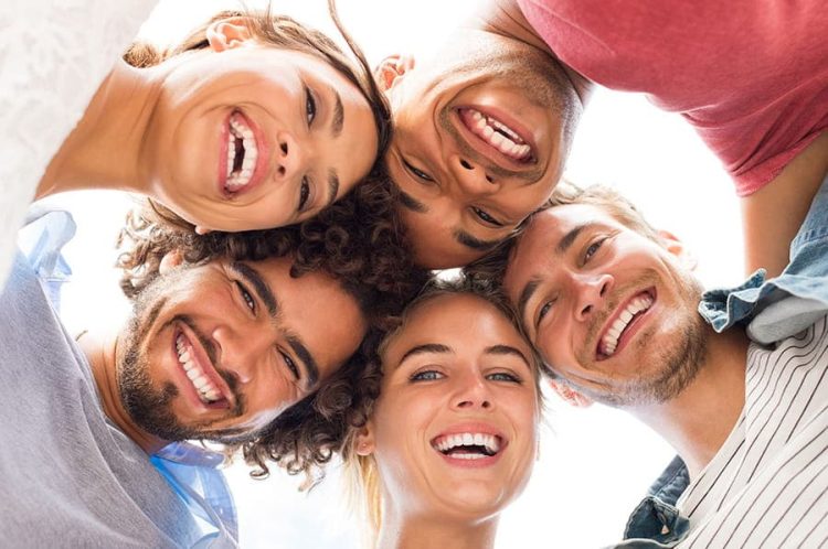Grupo de cinco personas sonriendo, destacando sonrisas saludables, representando la importancia de la est&eacute;tica dental en tratamientos en La Cl&iacute;nica Dental.