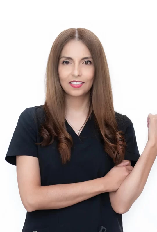 Mujer dentista con cabello largo y lacio, vestida con uniforme negro, sonriendo y mostrando confianza, representando el equipo profesional de La Clínica Dental Lindavista.