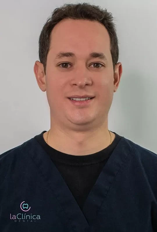 Dentista en uniforme de la Clínica Dental Lindavista, sonriendo, con fondo neutro, destacando su profesionalismo y compromiso con la atención dental.