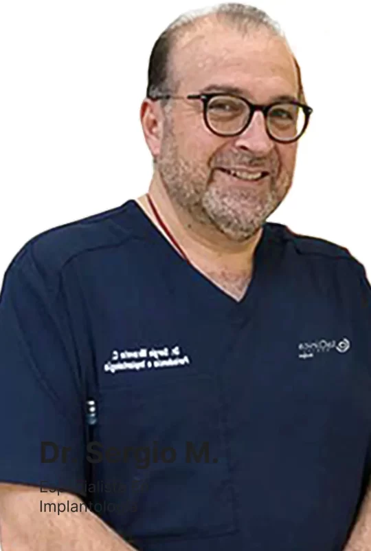 Dr. Sergio M., especialista en implantología, sonriendo en uniforme dental azul, parte del equipo de La Clínica Dental Lindavista.